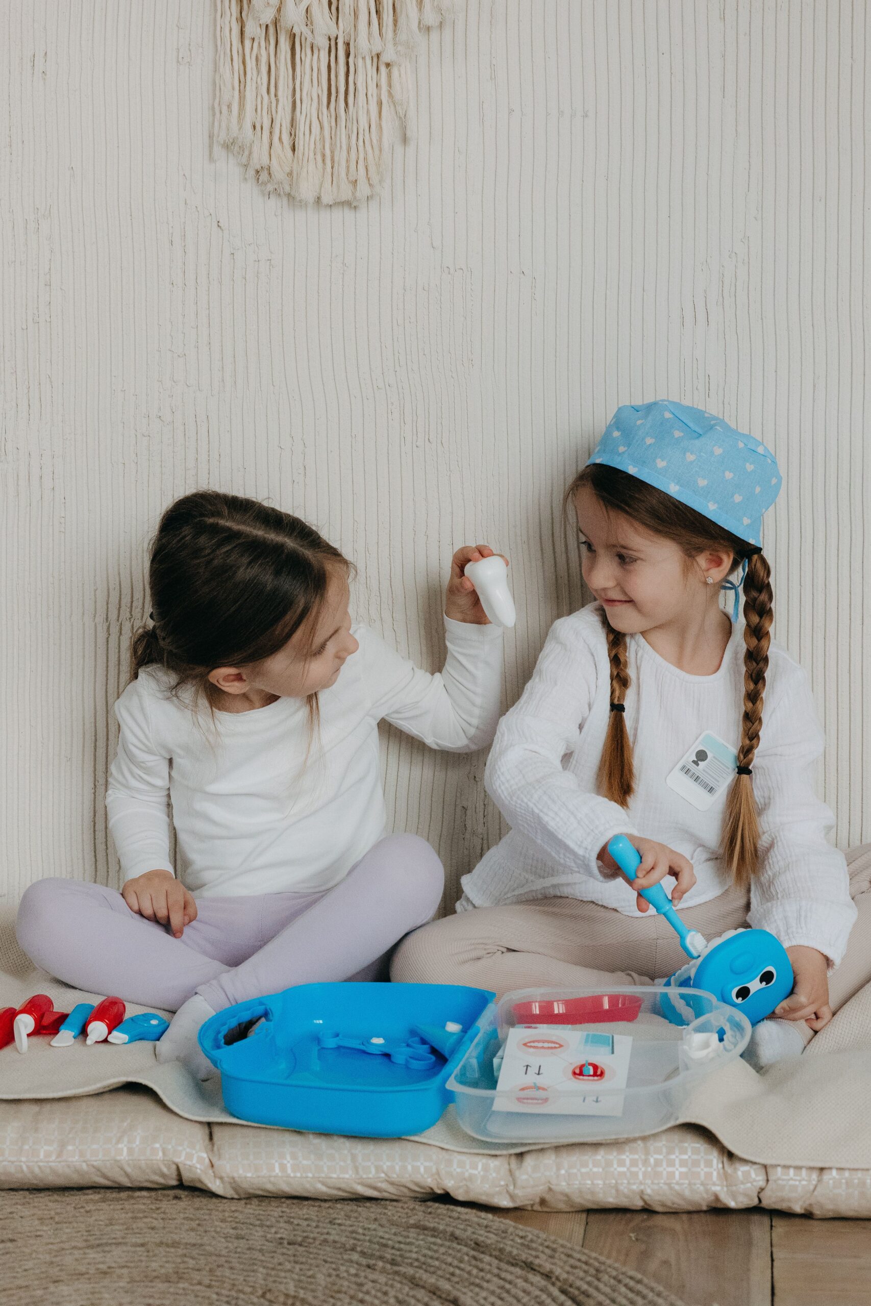 Two young girls playfully pretending to be a dentist and patient, creating a fun and educational scene indoors.